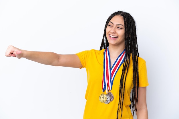 Tienermeisje met vlechten en medailles over geïsoleerde roze achtergrond die een duim omhoog gebaar geeft