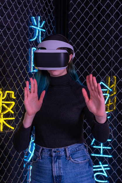 Tienermeisje met vr-headset is in virtual reality cyberspace futuristische neon kleurrijke achtergrond. Het concept van de metaverse, virtual reality, virtueel sociaal universum. Toekomstige digitale technologieën.