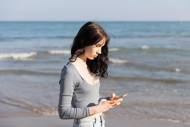 Tienermeisje neemt foto op haar mobiele telefoon aan de zeekust bij zonsopgang