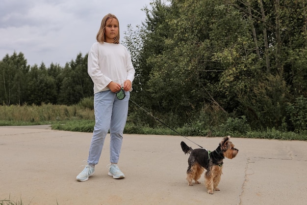 Tienermeisje op een wandeling in het zomerpark met haar huisdier yorkshire terriër. kind dat een hond uitlaat