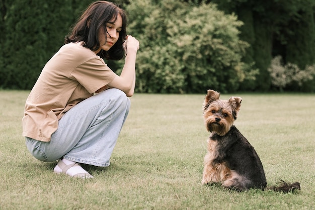 Tienermeisje op een wandeling in het zomerpark met haar huisdier Yorkshire Terriër Kind loopt een hond