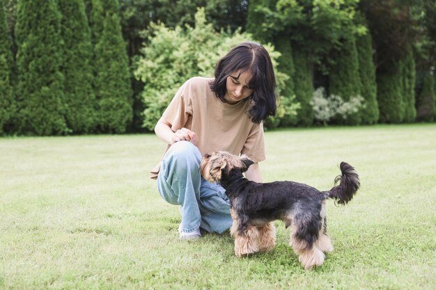 Tienermeisje op een wandeling in het zomerpark met haar huisdier Yorkshire Terriër Kind loopt een hond