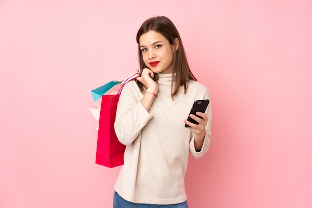 Tienermeisje op roze holding het winkelen zakken en een mobiele telefoon