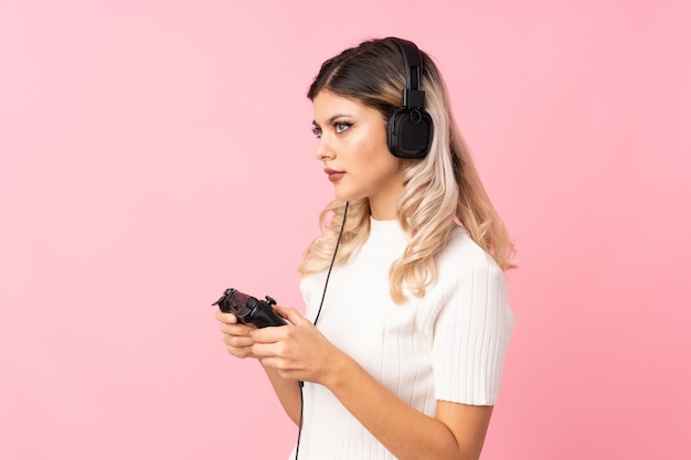 Tienermeisje over het geïsoleerde roze spelen als achtergrond bij videospelletjes