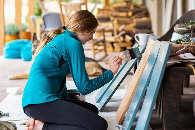 Tienermeisje schildert houten planken blauw