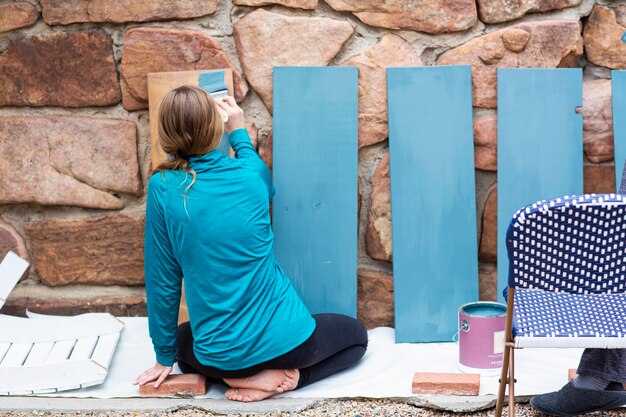 Tienermeisje schildert houten planken blauw