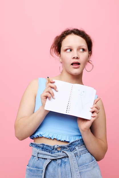 Tienermeisje schrijven in een rood notitieboekje met een pen studie roze kleur achtergrond ongewijzigd