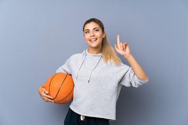 Tienermeisje speelbasketbal over grijze muur die een groot idee benadrukken