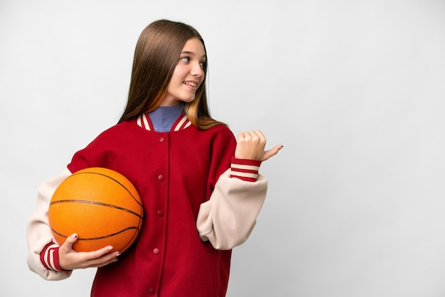 Tienermeisje speelt basketbal over een geïsoleerde witte achtergrond die naar de zijkant wijst om een product te presenteren