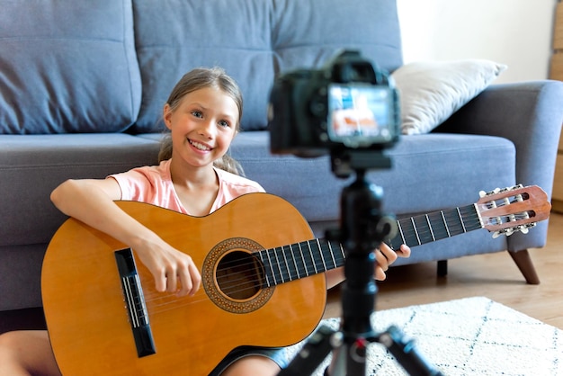 Tienermeisje speelt een klassieke gitaar opname video voor kanaal blog Hobbies voor meisjes muziek kunst onderwijs online communicatie met kinderen en adolescenten