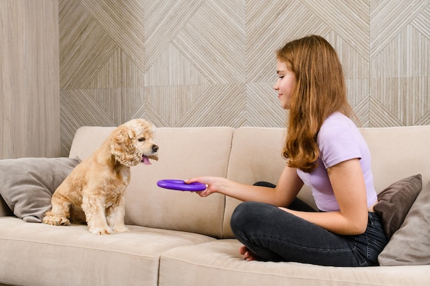 Tienermeisje speelt met spaniel terwijl ze op de bank in de woonkamer zit