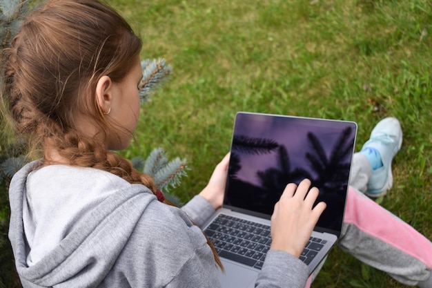 Tienermeisje studeren op een laptop Afstandsonderwijs Gelukkig schoolmeisje in Park met computer