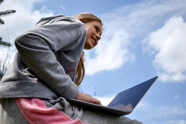 Tienermeisje studeren op een laptop Afstandsonderwijs Gelukkig schoolmeisje in Park met computer