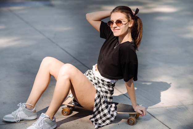 Tienermeisje zit en koelt op het skateboard in het skaterspark