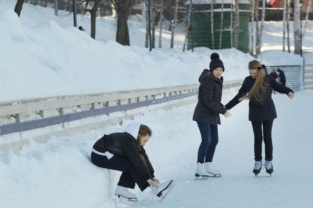 Tienermeisje zittend op sneeuw die de veters op de schaatsen aanspant