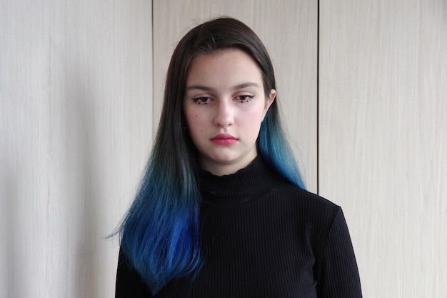 Tienerproblemen Portret van een verdrietig boos meisje met blauw haar en druipende mascara op haar ogen op een houten achtergrond