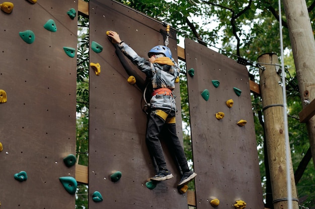 Tieners die de muur beklimmen in een avontuurpark, een hindernisbaan passeren, een hoog touwpark