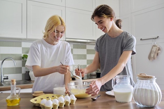 Tieners, jongen en meisje koken samen pannenkoeken in de keuken