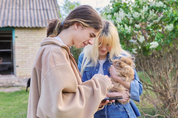 Tieners met decoratief konijn in handen praten en kijken naar smartphone
