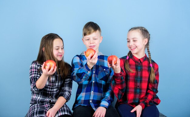 Tieners met een gezonde snack Gezonde voeding en vitaminevoeding Eet fruit en wees gezond Groepstieners houden appels Gezonde levensstijl Jongens en meisjes vrienden in soortgelijke geruite kleding eten appel