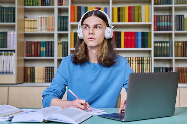 Tieners studeren in de bibliotheek met een laptop.