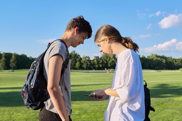 Tieners vrienden praten kijken naar smartphone scherm