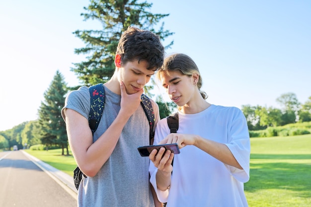 Tieners vrienden praten kijken naar smartphone scherm