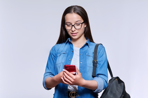 Tienerstudent die met rugzaksmartphone het scherm op lichte achtergrond bekijken