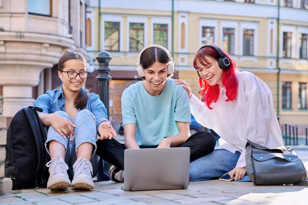 Tienervrienden die in hoofdtelefoons laptop bekijken