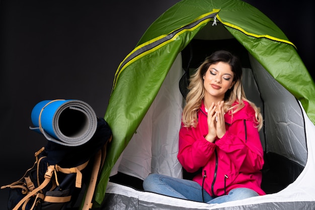 Tienervrouw binnen een het kamperen groene tent die bij het zwarte muur plannen wordt geïsoleerd