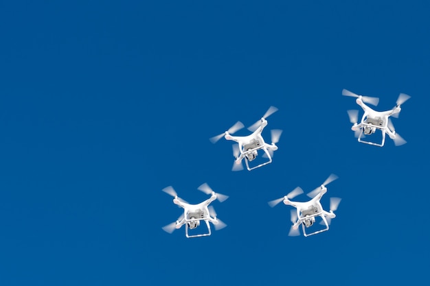 Tientallen drones zwermen in de blauwe lucht. quadcopters drones met digitale camera in de lucht boven de stad.