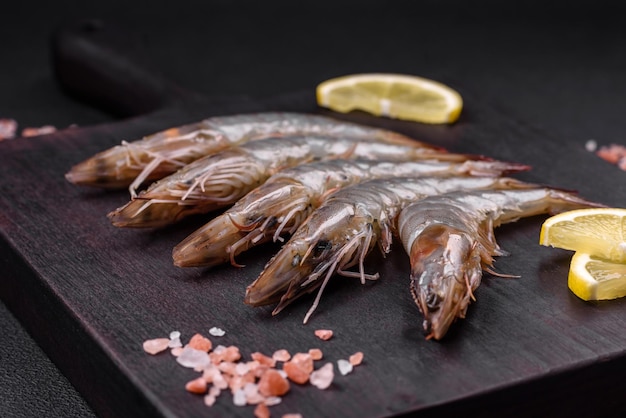 Tiger prawn or langoustine raw with spices and salt on a wooden cutting board