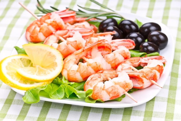 Tiger prawns on a skewer with olives and lemon