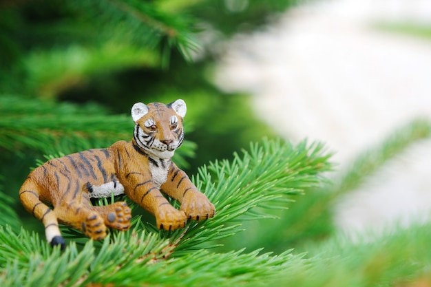 A tiger statuette on a green natural spruce. happy new year.\
the tiger is the symbol of the year 2022.