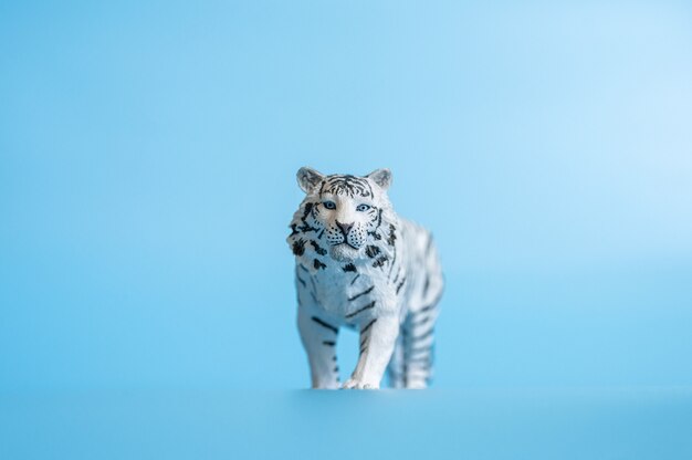 Тигр, символ 2022 года. пластиковая белая игрушка фигурка тигра на синем фоне