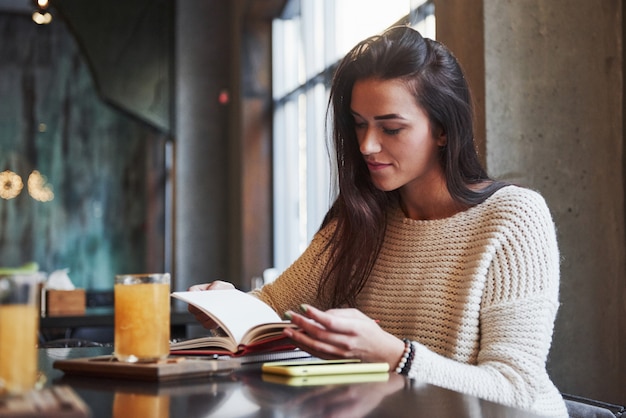 Tijd om nieuwe interessante informatie te lezen en te ontvangen terwijl u in het restaurant zit met een tafel en een geel drankje erop