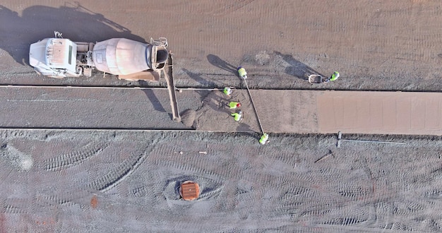 Tijdens de aanleg van een trottoir giet een betonmixwagen cement tijdens het storten van cement door arbeiders