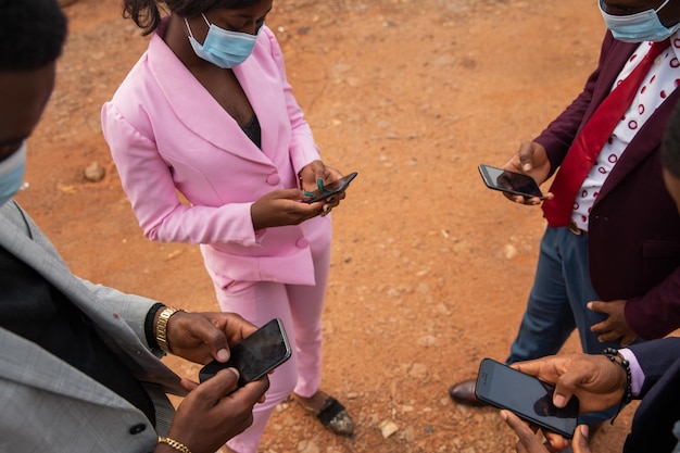 Tijdens de Covid 19-pandemie gebruiken vier collega's hun mobiele telefoon tijdens een werkpauze