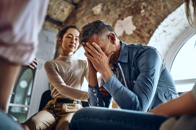 Tijdens groepstherapiesessies bieden deelnemers die huilende wanhopige man ondersteunen psychologische hulp door te praten bemoedigende woorden delen mentale pijn proberen te helpen worstelen met verslavingsbehandeling