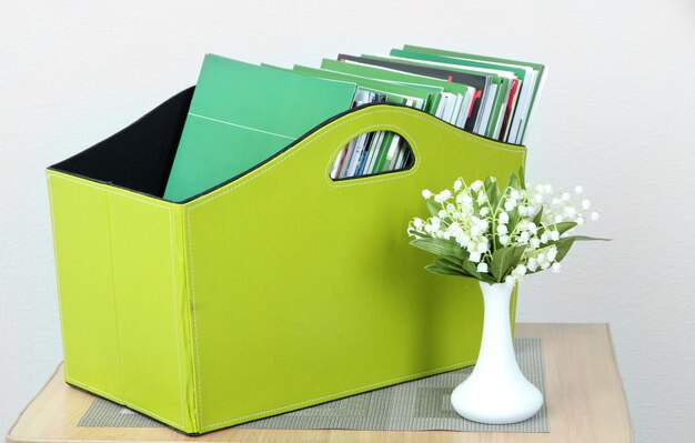 Foto tijdschriften en mappen in groene doos op nachtkastje in kamer