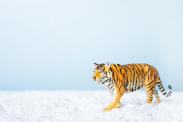 Tijgersymbool van het Chinese nieuwe jaar 2022. Beeldje van tijger in sneeuw op blauwe achtergrond. Kerst wenskaart. Banner, kopieer ruimte.