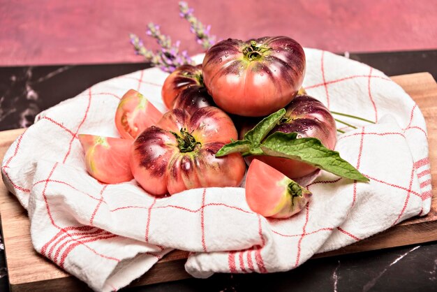 Tijgertomaat op een snijplank met basilicumbladeren op houten achtergrond Kopieer de ruimte Verse tomaat verspild om te koken Tomaat met druppels water