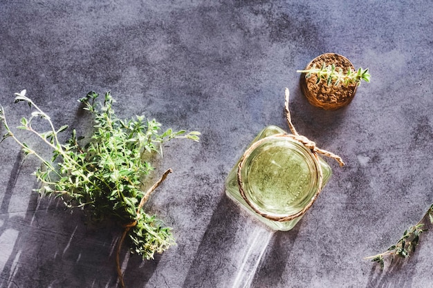 Tijm etherische olie in open fles kurk en verse Thymus planten op grijze marmeren tafel plat gelegd