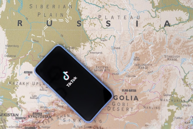 Il logo tik tok sullo schermo dello smartphone sullo sfondo della mappa della russia