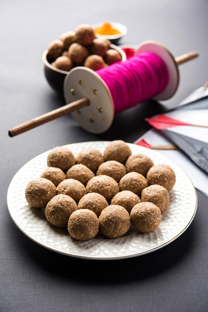 Til Gul OF Sweet Sesame Laddu met Fikri en Kite met haldi Kumkum voor Makar Sankranti-festival over humeurige achtergrond, selectieve focus