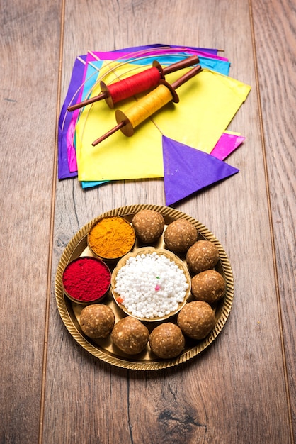 Til Gul OR Sweet Sesame Laddu met miniatuur Fikri en Kite-model met haldi Kumkum en suikerkristallen voor Makar Sankranti-festival over humeurige achtergrond, selectieve aandacht