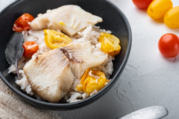 Tilapia fish with basmati rice and cherry tomatoes, in bowl, on white table