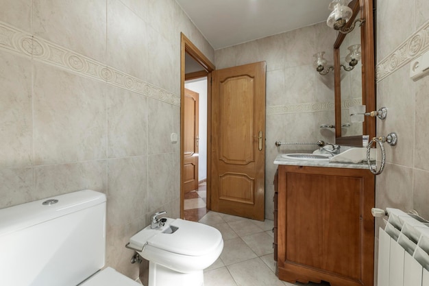 흰색 알루미늄 트림과 일치하는 받침대 및 샤워실이 있는 회색 트림의 흰색 도자기 싱크대가 있는 타일 욕실