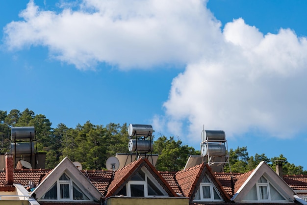 Tiled roof of a house with satellite dishes and tanks for heating water