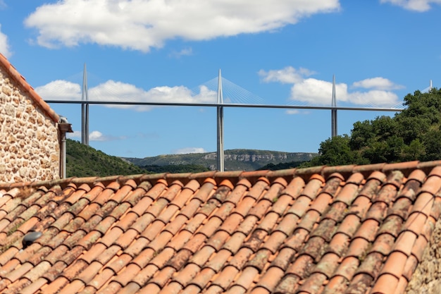 Tiled roof and stone wall from middle ages and Millau Viaduct from 21 century Aveyron Occitania
